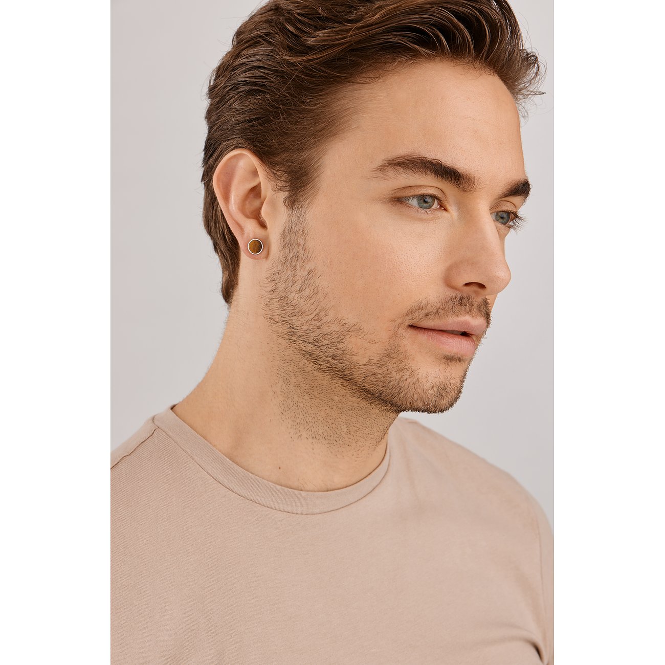 Een Caï 925 zilveren oorsteker met tijgeroog, ovaalvormig, gedragen aan een mannelijk oor.