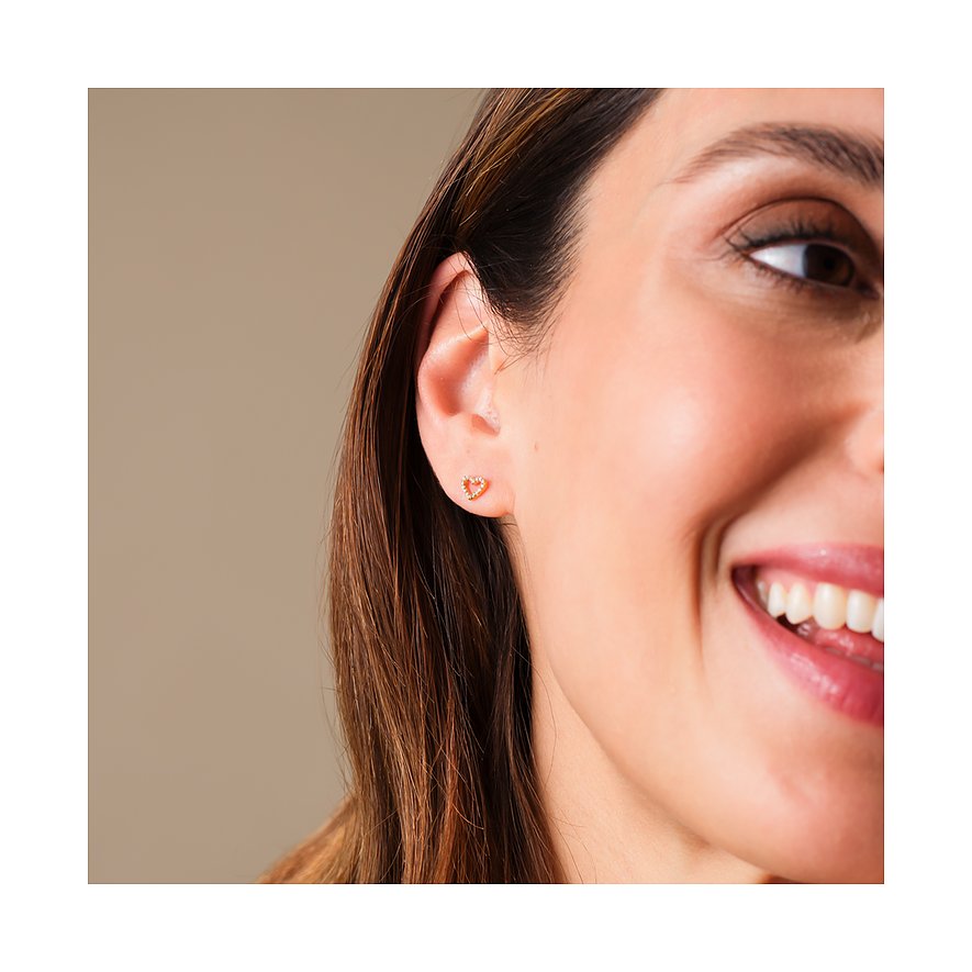 Eine Frau mit einem kleinen FAVS Ohrstecker aus Gelbgold mit Zirkonia in Herzform am Ohrläppchen.