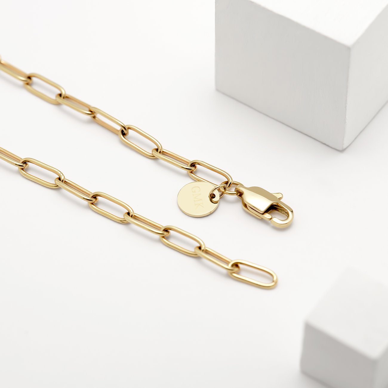 Schmalgliedrige goldene Guido Maria Kretschmer Halskette aus Edelstahl und Emaille mit GMK-Logo und Karabiner.