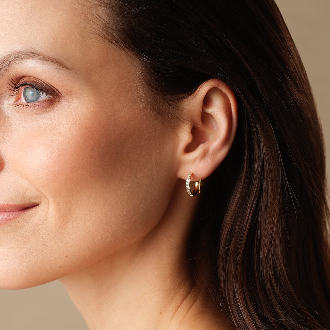 Een vrouw draagt een FAVS creool oorbel van goudkleurig roestvrij staal met zirkonia stenen.