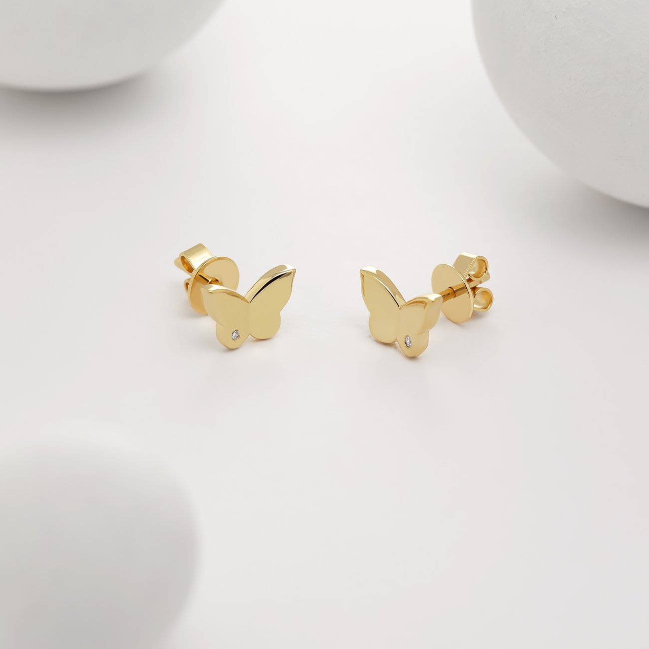 Ein Paar Schmetterlingsohrstecker von Guido Maria Kretschmer aus goldenem Silber, verziert mit einem kleinen Diamanten.