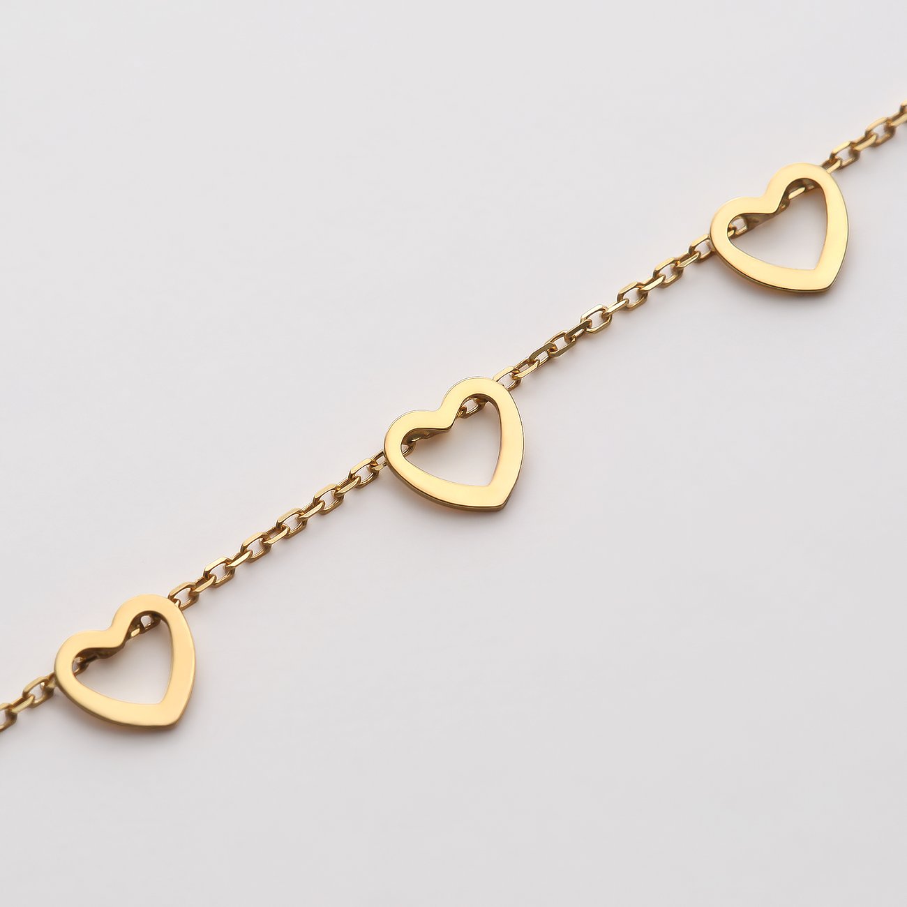 Nahaufnahme eines CHRIST Gelbgold 585 Armbands mit drei freistehenden Herz-Anhängern auf einer feinen Gliederkette.