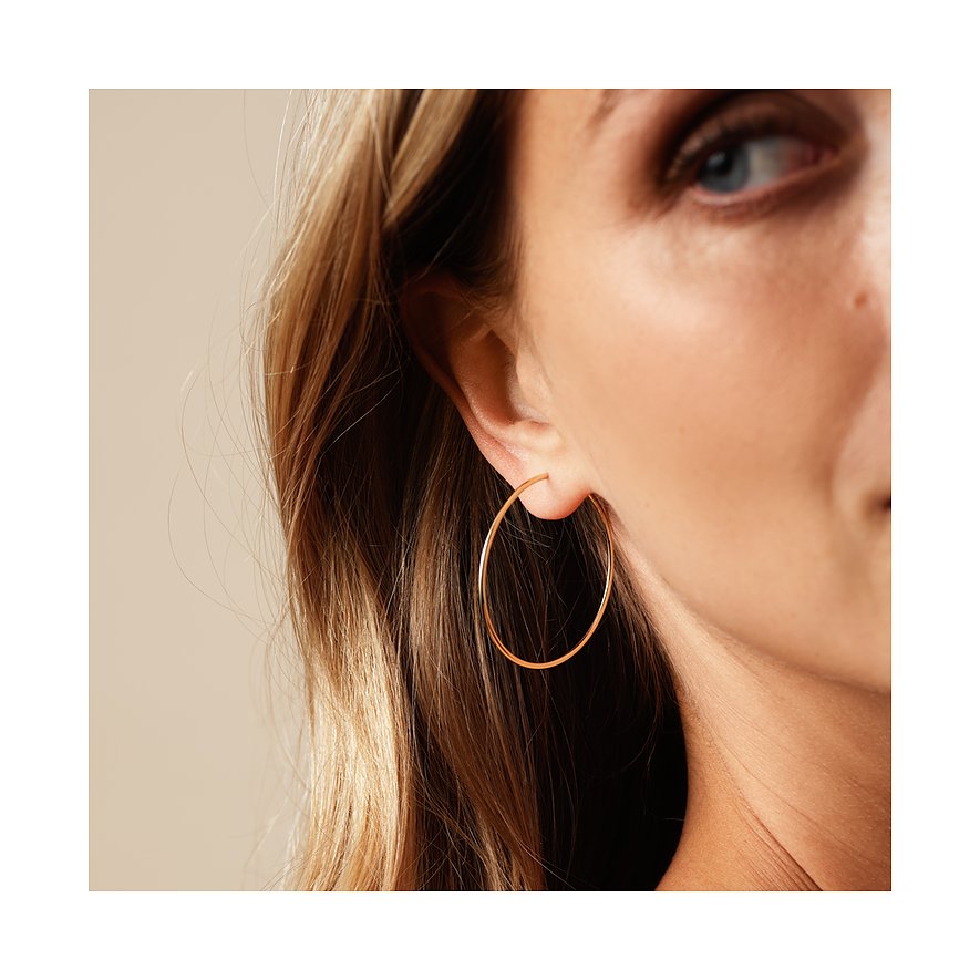 Gros plan d'une oreille portant une boucle d'oreille créole brillante en or jaune 585.