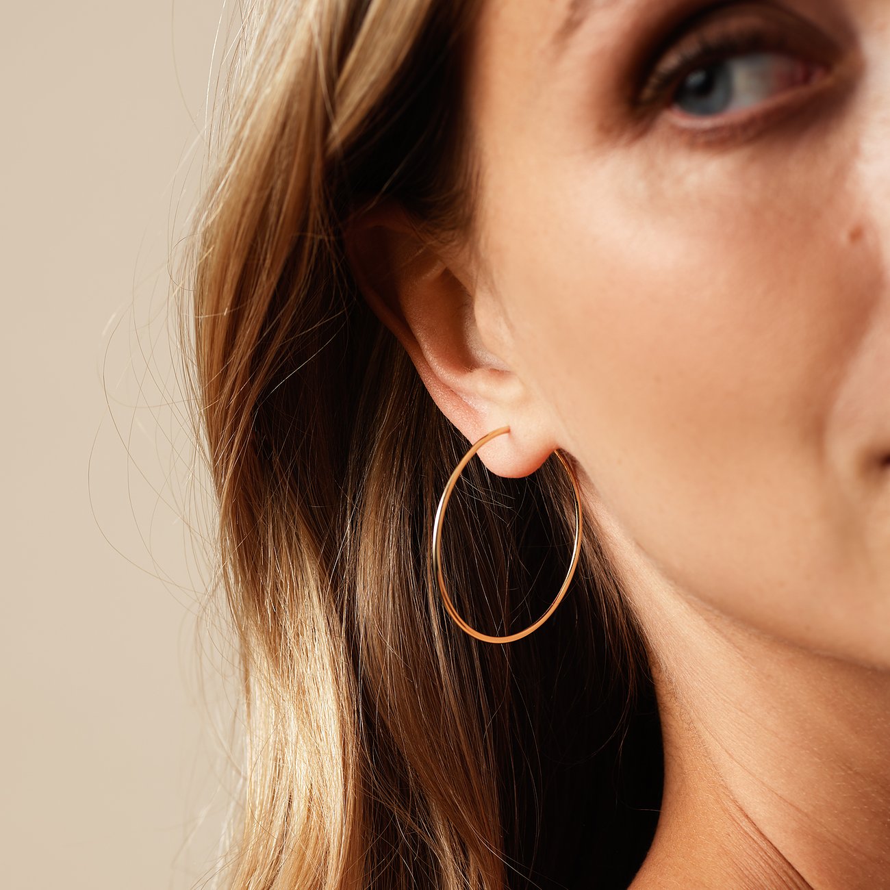 Gros plan d'une oreille portant une boucle d'oreille créole brillante en or jaune 585.