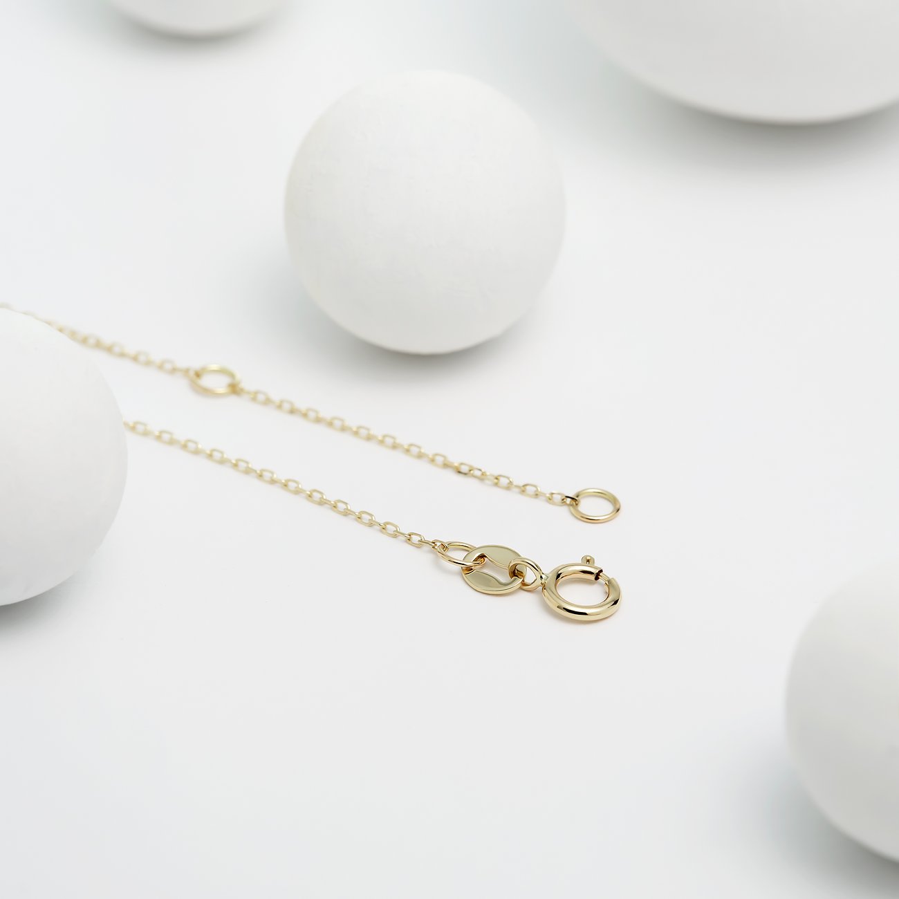 Detailaufnahme einer CHRIST Halskette aus Gelbgold mit einem Diamanten, die auf einer weißen Oberfläche liegt.