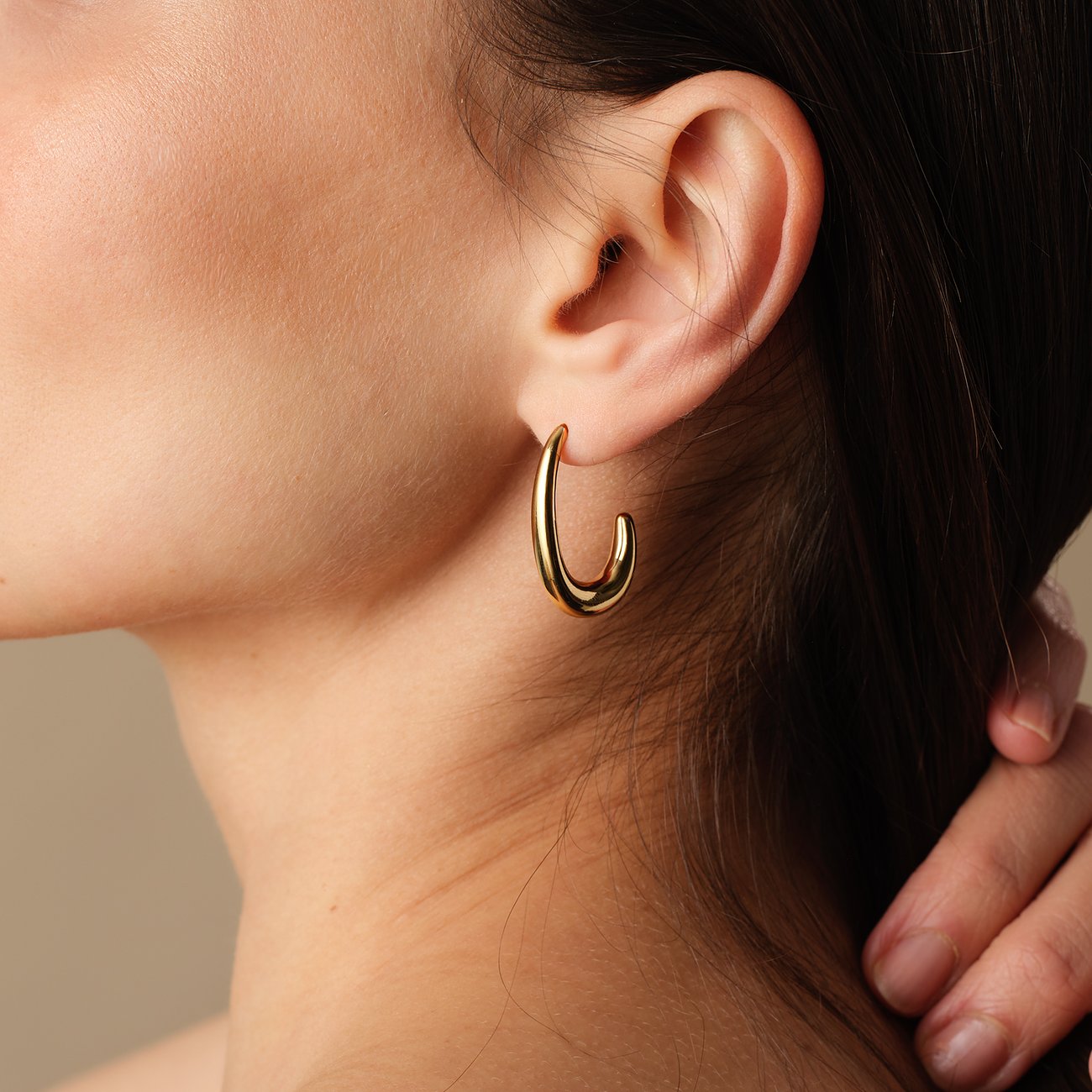 FAVS Ohrschmuck aus gelbvergoldetem Edelstahl, leicht hakenförmig, am Ohr einer Person getragen.