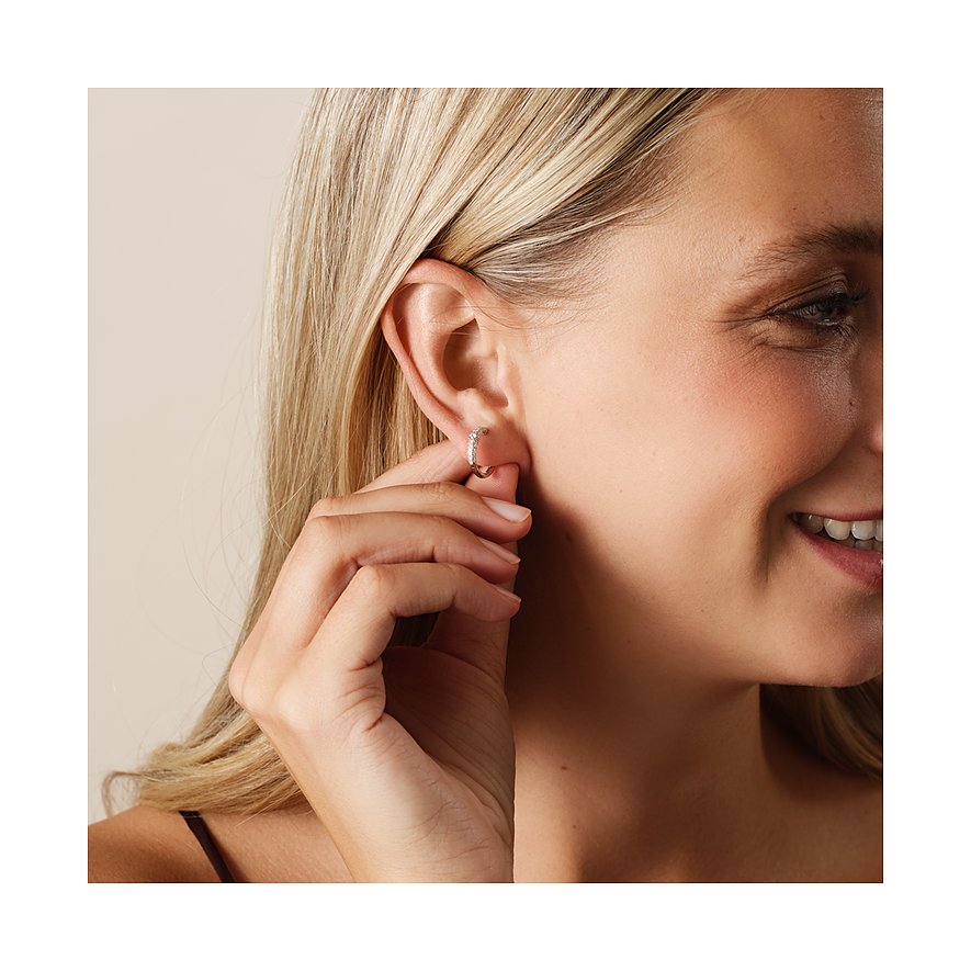 Nahaufnahme einer lächelnden Frau, die einen kleinen weißgoldenen CHRIST Ohrring mit Diamanten trägt.
