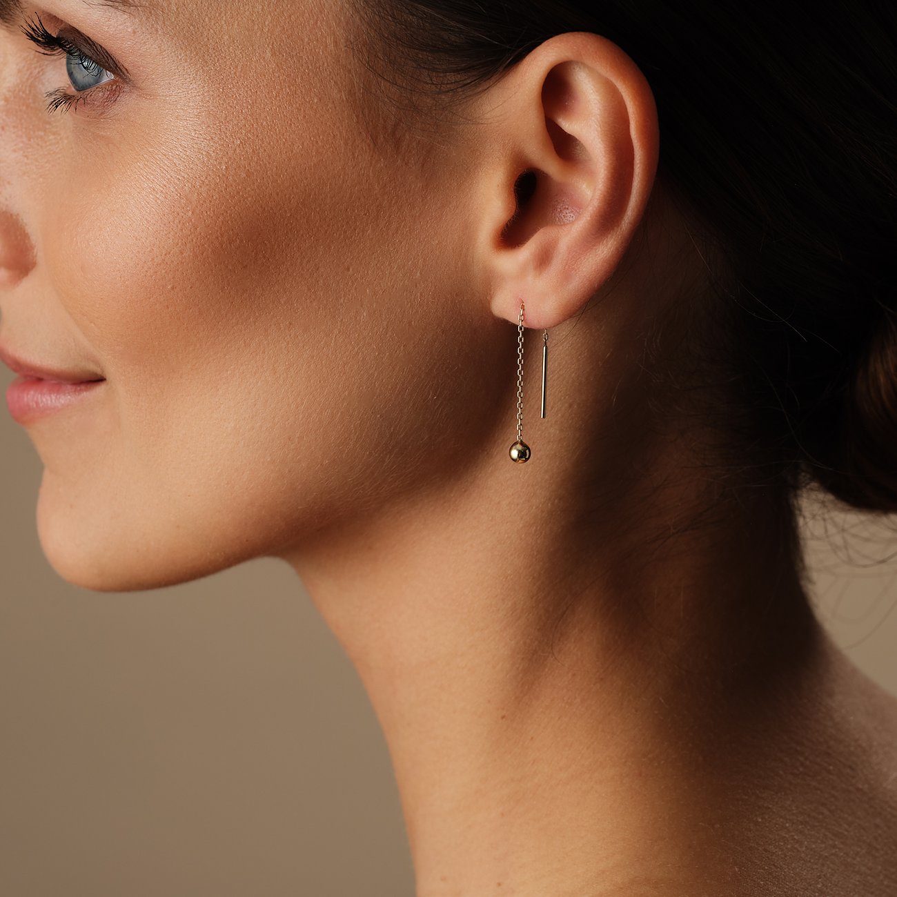 FAVS Ohrschmuck aus 375er Gelbgold mit einer runden Kugel und einem Stab auf einer Frau getragen