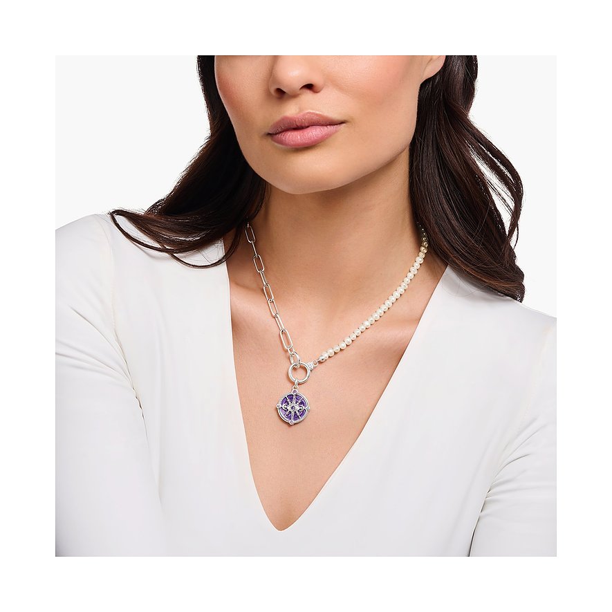 Frau trägt silberne Thomas Sabo Kette mit rundem Anhänger aus Emaille, lilafarbenem Glasstein und Perlen.
