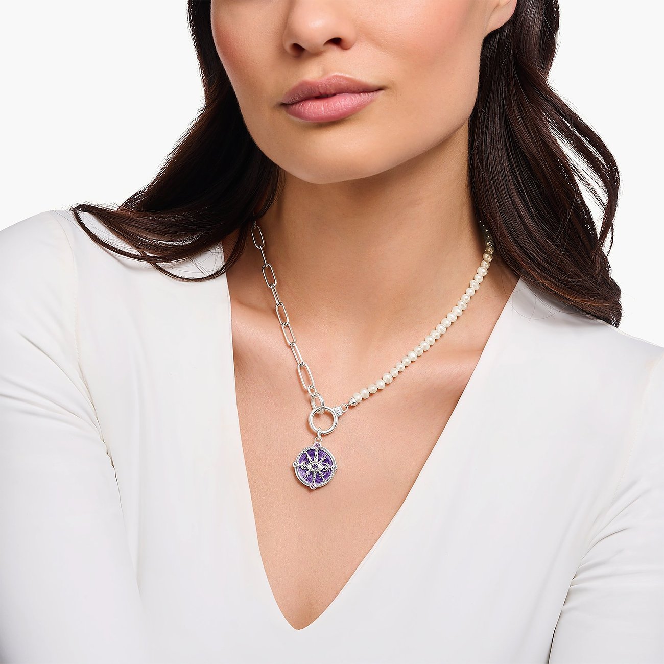 Frau trägt silberne Thomas Sabo Kette mit rundem Anhänger aus Emaille, lilafarbenem Glasstein und Perlen.