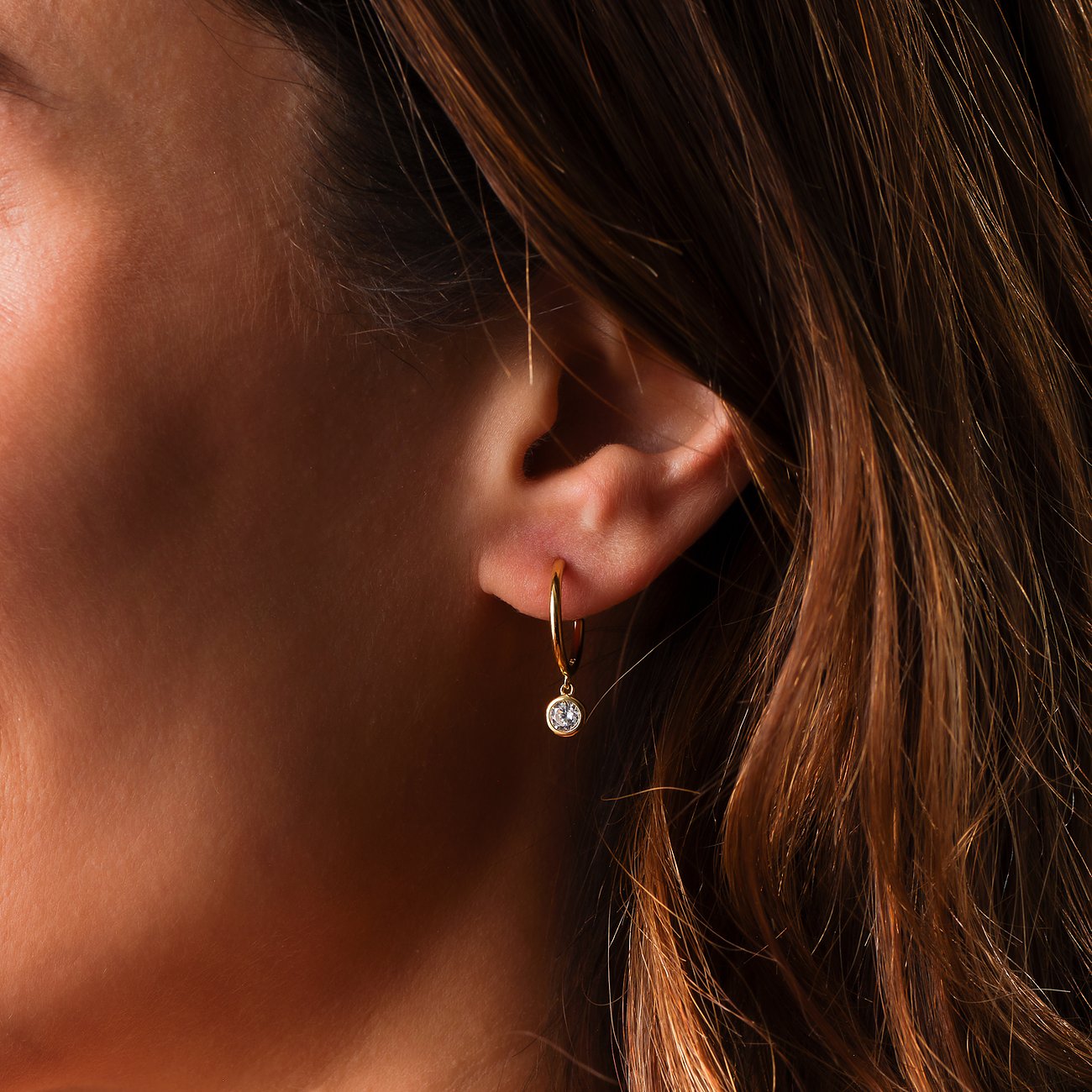 FAVS Ohrschmuck aus Silber: ein goldfarbener Creolen-Ohrring mit einem einzelnen, hängenden Zirkonia-Farbstein.