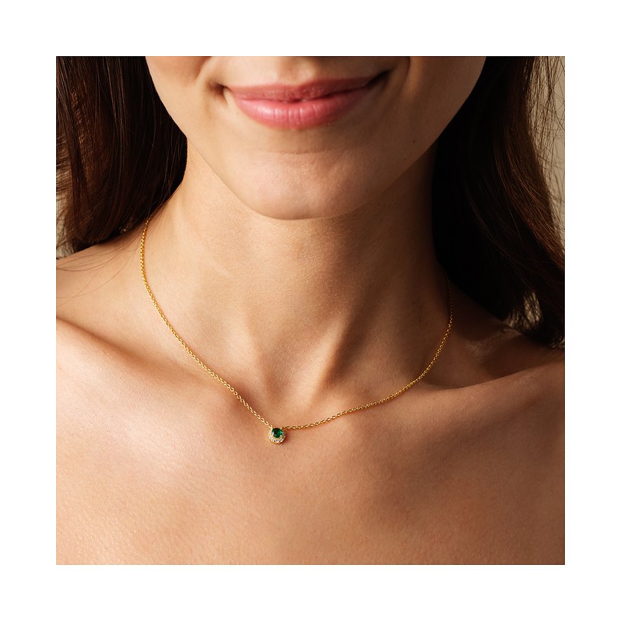 En kvinna bär ett FAVS halsband i guldpläterat 925 sterlingsilver med en rund grön zirkoniasten.