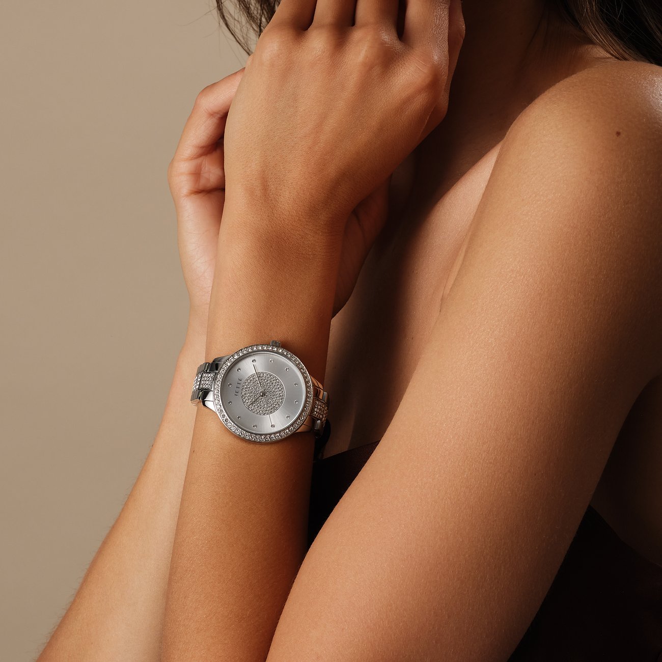 Am Handgelenk einer Frau ist eine JETTE Damenuhr aus Edelstahl mit einem Besatz aus Kristallen in Nahaufnahme zu sehen.