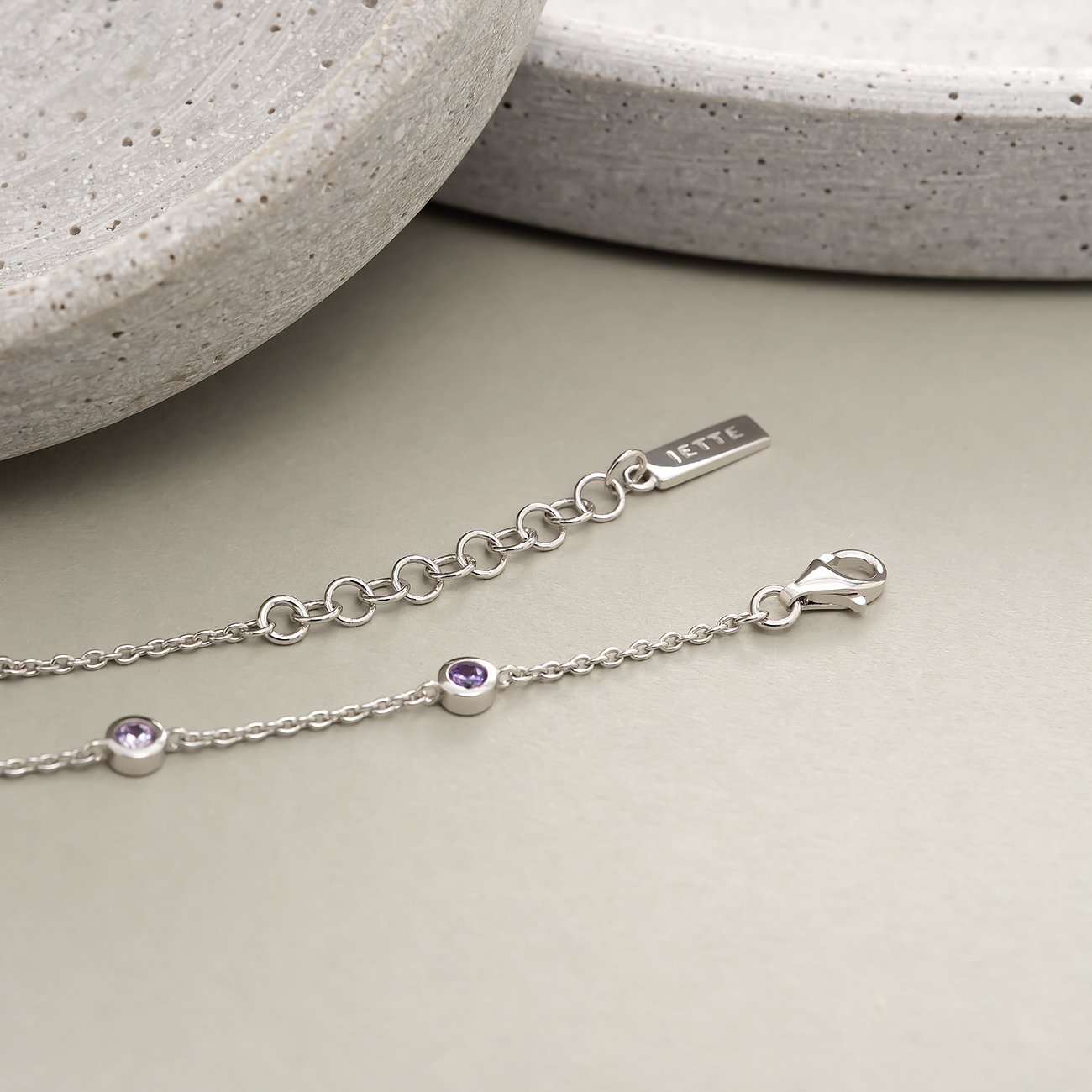 Nahaufnahme eines JETTE Armbands aus recyceltem 925er Silber mit lila Zirkonia-Farbsteinen und Verschluss.