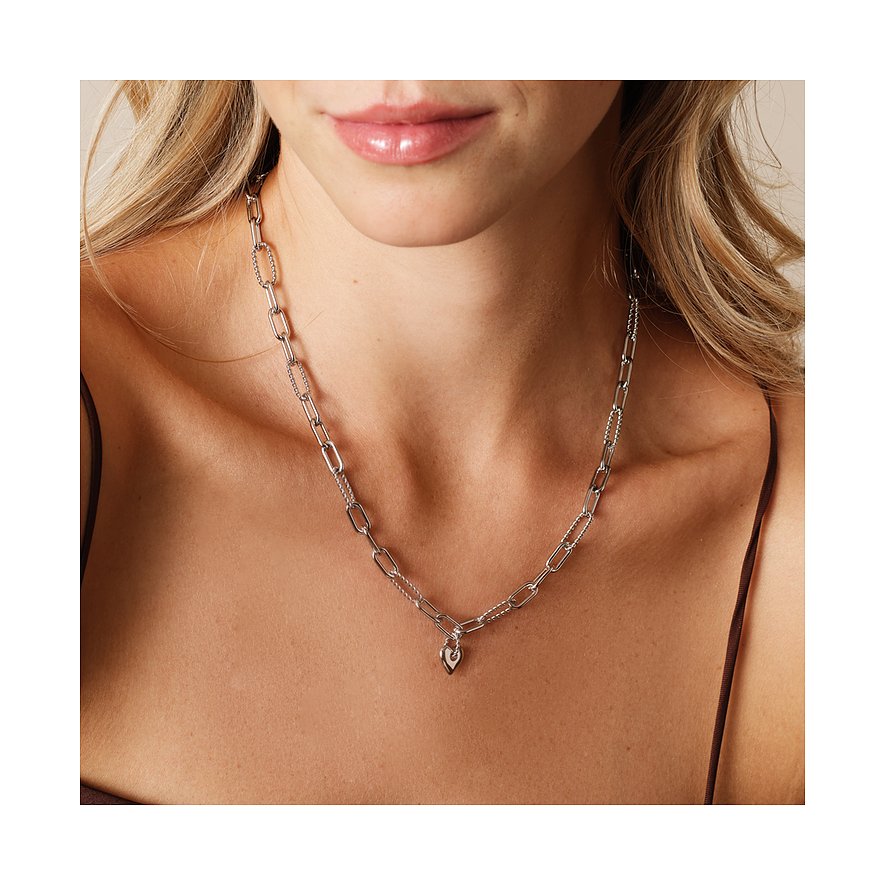 Frau trägt Guido Maria Kretschmer Edelstahlkette mit verschiedenen Kettengliedern und kleinem Herzanhänger.