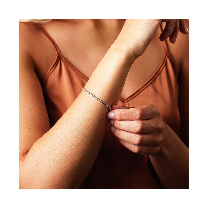 Am Arm einer Frau das lange, gedrehte CHRIST Armband aus 585 Weißgold. Ihre Hand berührt das geflochtene Armband.