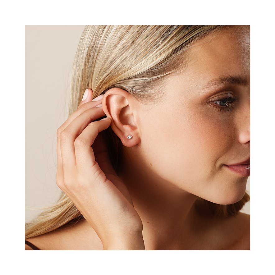 Ein blondes Model trägt einen kleinen Ohrstecker von CHRIST aus Weißgold mit einem Diamanten im Ohr.