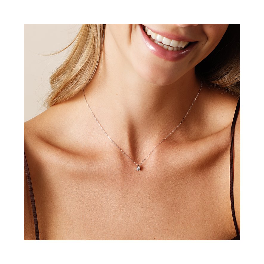 Nahaufnahme einer lächelnden Frau, die eine CHRIST Halskette aus 585er Weißgold mit einem zentralen Diamanten trägt.