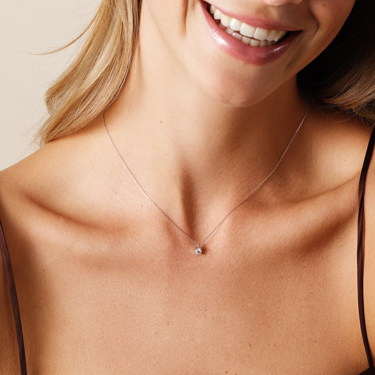 Nahaufnahme einer lächelnden Frau, die eine CHRIST Halskette aus 585er Weißgold mit einem zentralen Diamanten trägt.