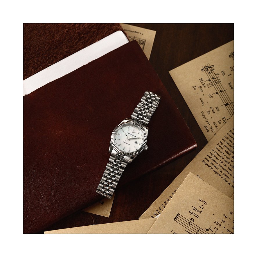 Eine Lucien Rochat Damenuhr aus Edelstahl mit einem weißen Zifferblatt liegt auf einem braunen Notizbuch.