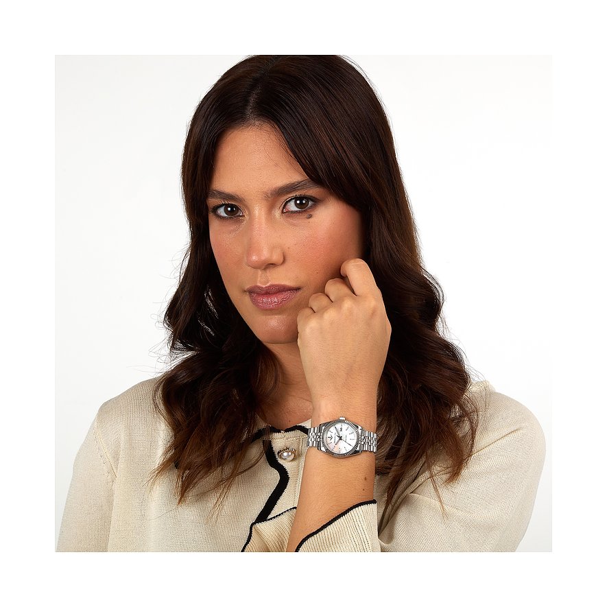 Eine Frau mit dunklen Haaren und einem beigen Cardigan trägt eine Lucien Rochat Damenuhr aus Edelstahl am linken Handgelenk.