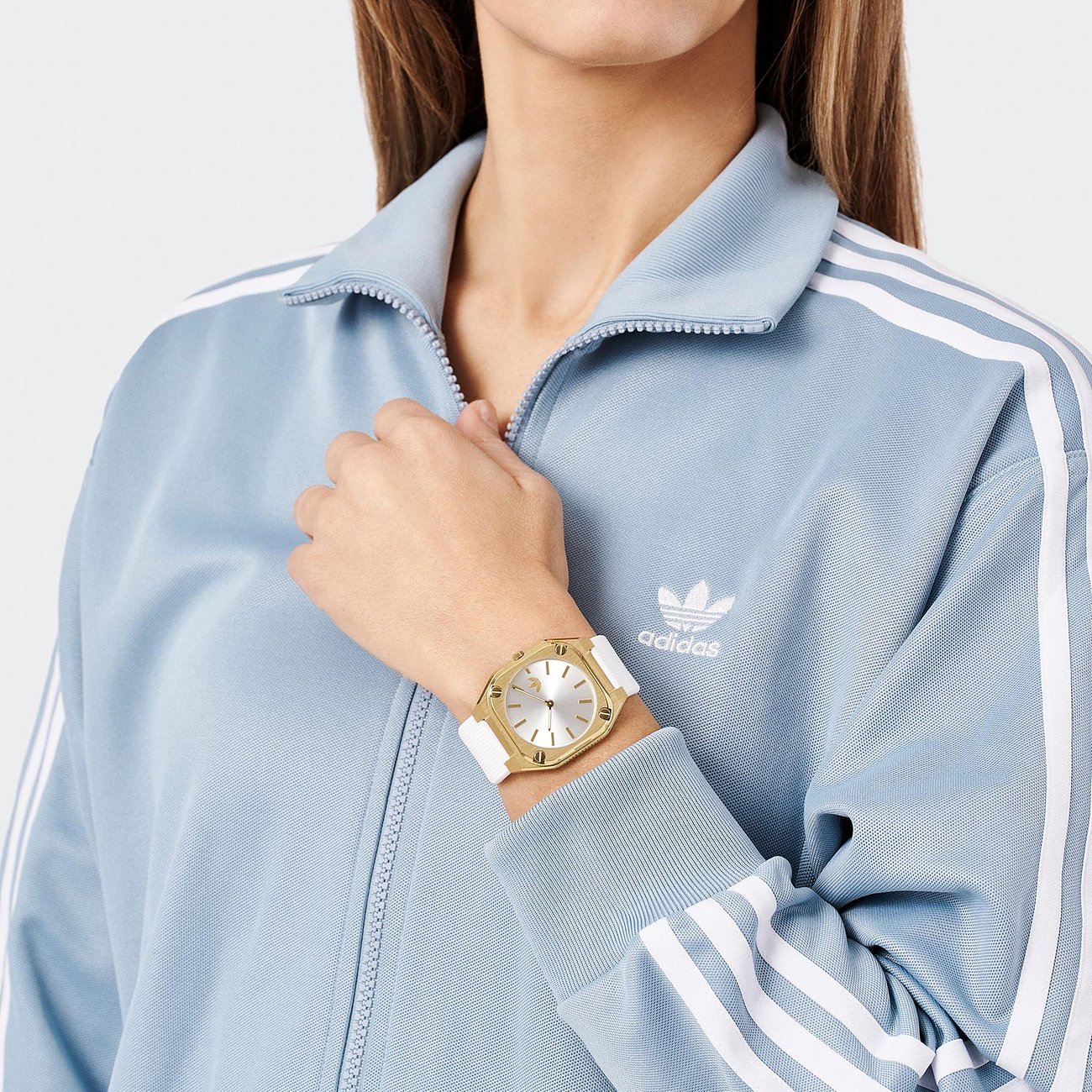 Montre unisexe Adidas avec boîtier en acier inoxydable, dorée et bracelet blanc.