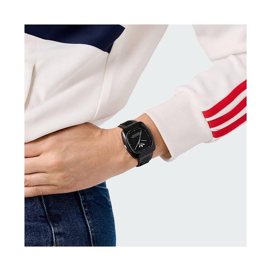 Montre unisexe Adidas avec boîtier en céramique, cadran noir et affichage analogique.