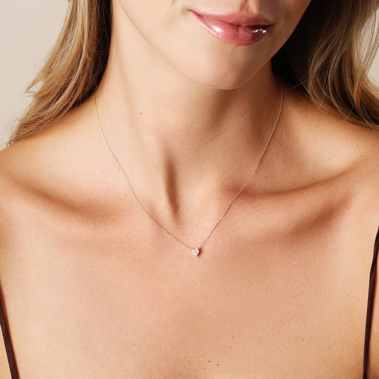 Eine Frau trägt eine CHRIST Herzkette aus 585 Gelbgold mit einem kleinen Diamanten in Herzform auf der Brust.
