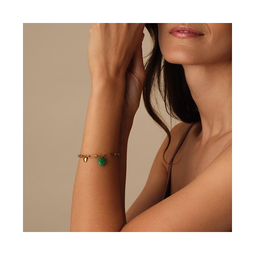 Bracelet doré en acier inoxydable Guido Maria Kretschmer, cristal vert en forme de cœur, au bras d'une femme.