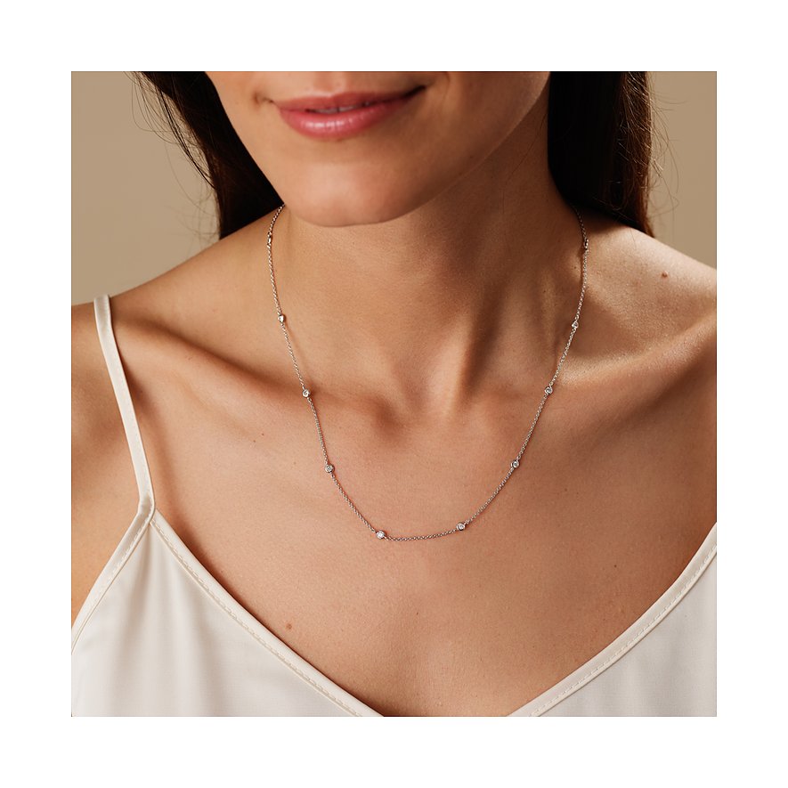 Nærbillede af kvinde, der bærer en delikat CHRIST-halskæde af genbrugt 925 sølv med zirconia farvesten.