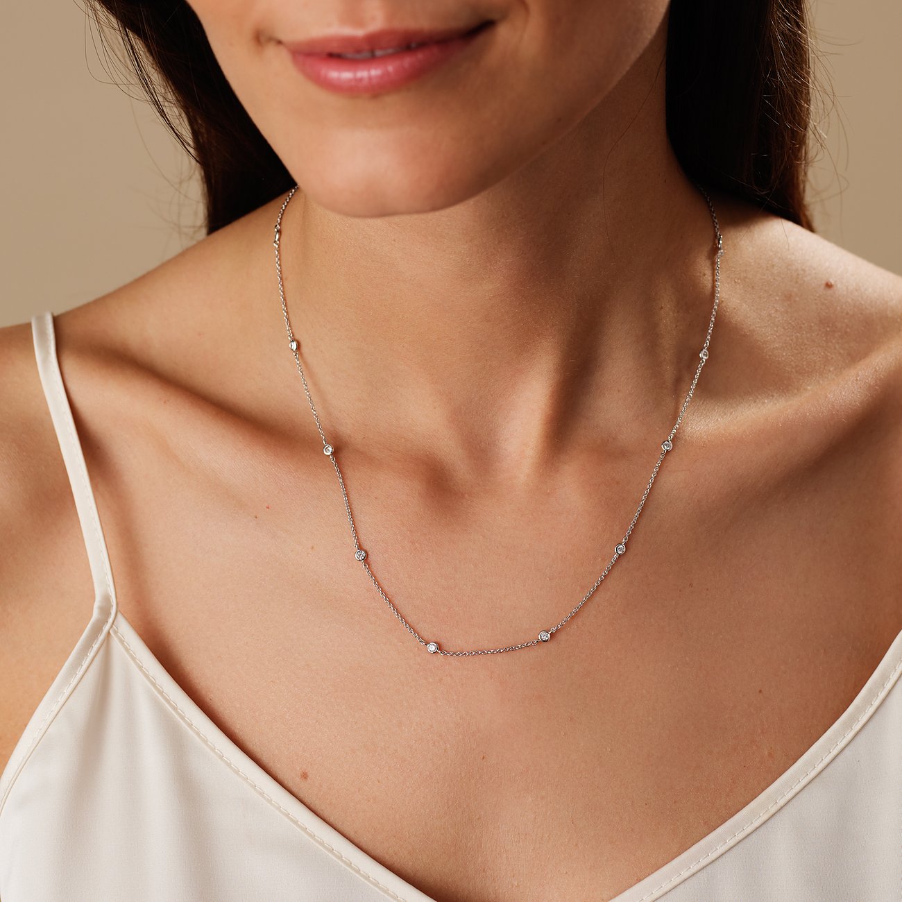 Nærbillede af kvinde, der bærer en delikat CHRIST-halskæde af genbrugt 925 sølv med zirconia farvesten.