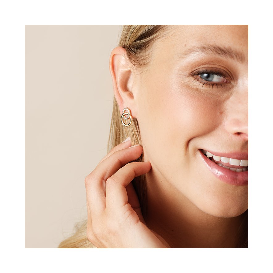 Eine Nahaufnahme einer lachenden Frau, die einen einzelnen CHRIST Ohrschmuck aus recyceltem Silber mit Zirkonia trägt.