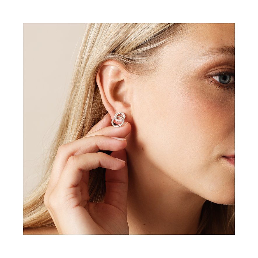 Nahaufnahme eines CHRIST Ohrsteckers aus 925 recyceltem Silber mit verschlungenen Ringen, dem Ohr einer Frau.