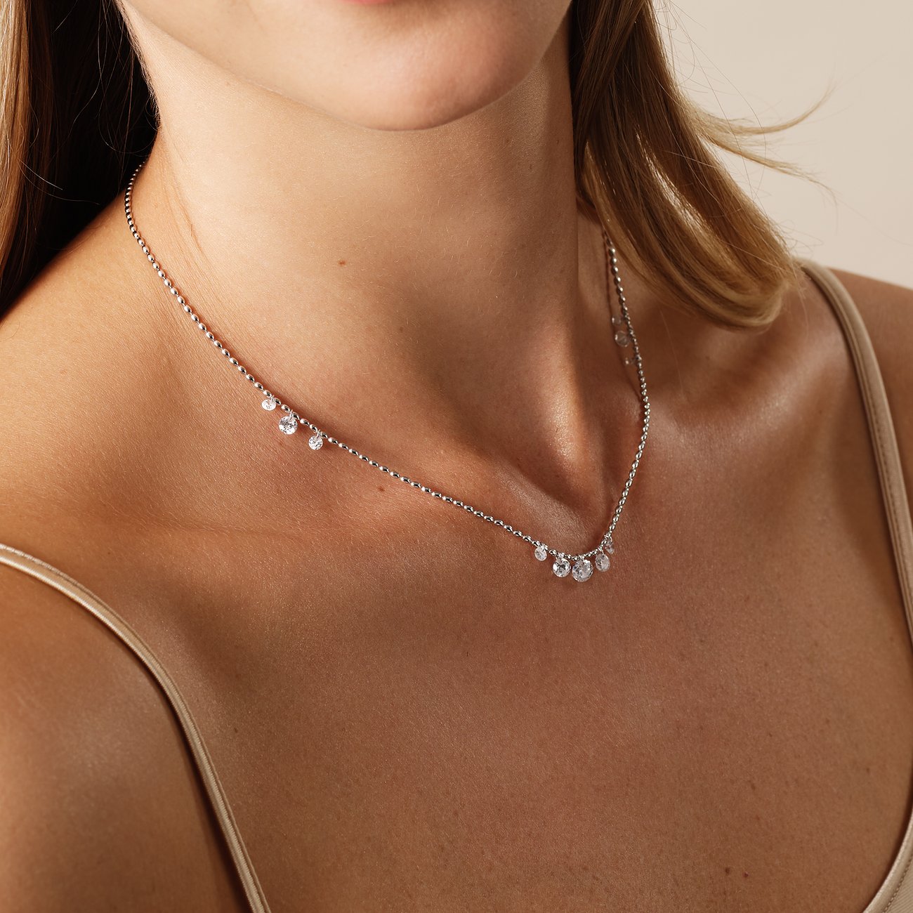 Nahaufnahme einer Frau, die eine CHRIST Halskette aus recyceltem Silber mit funkelnden Zirkonia-Farbsteinen trägt.