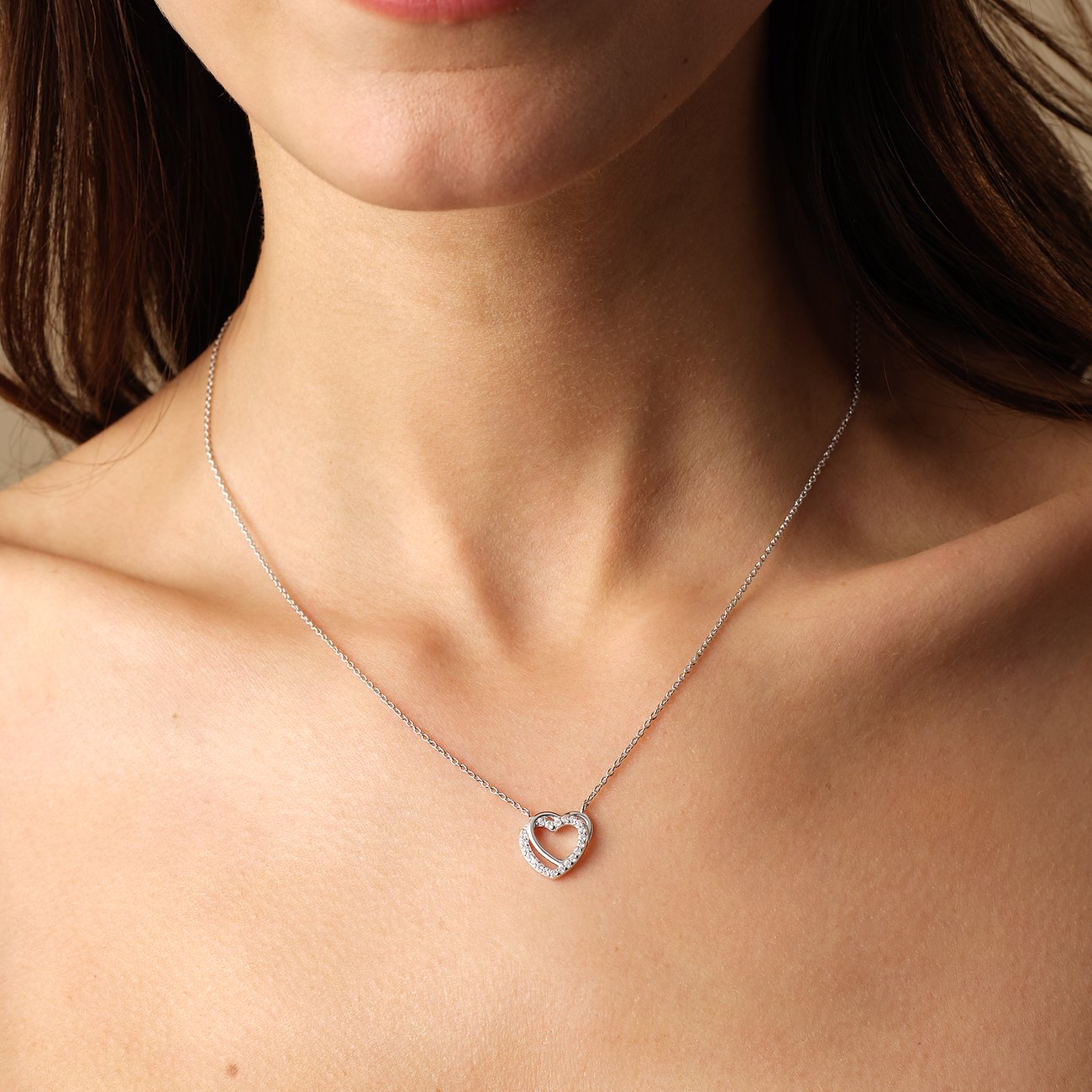 Une femme porte un collier cœur FAVS en argent 925 avec des pierres de zircon de couleur comme parure de cou.