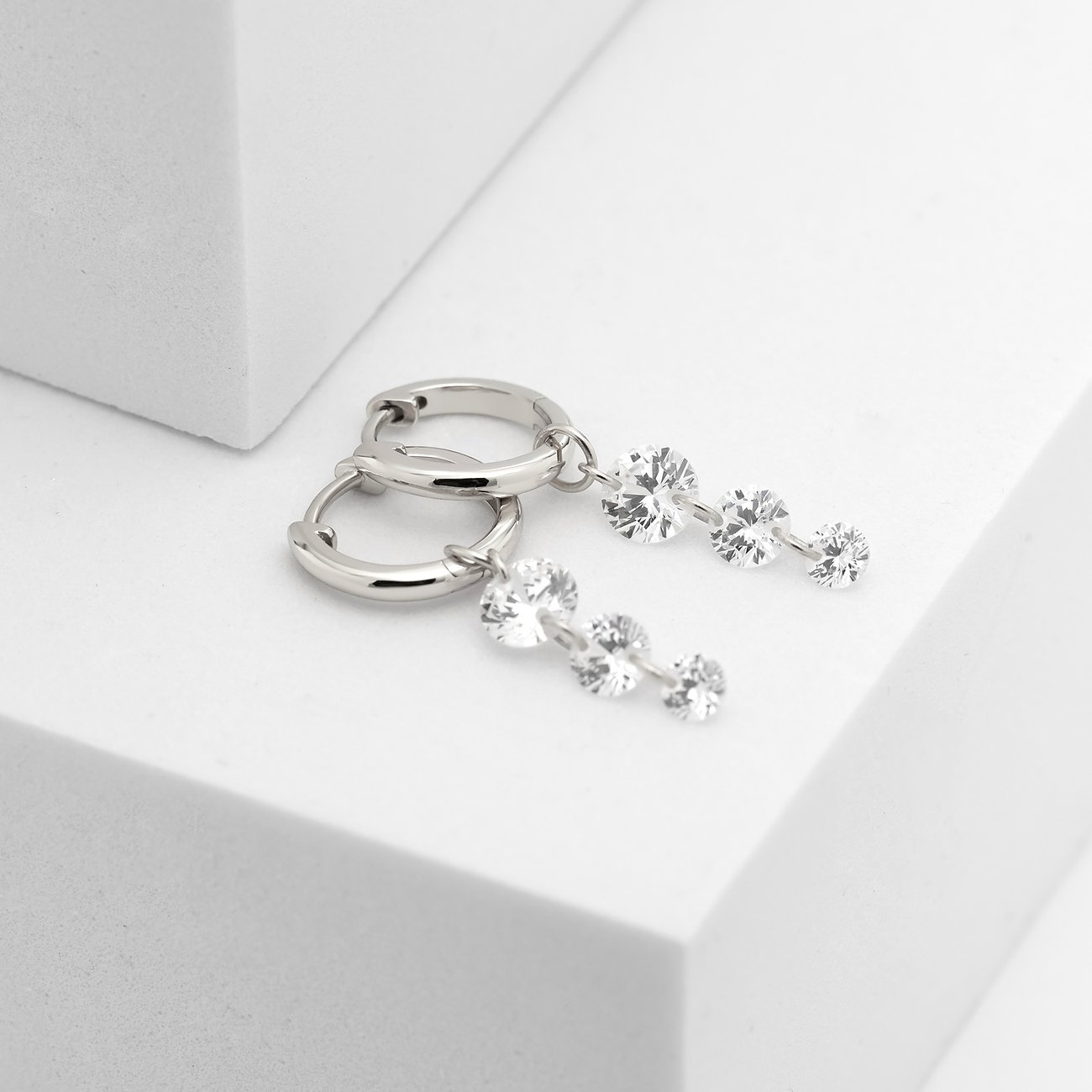 CHRIST Ohrschmuck aus recyceltem 925er Silber mit baumelnden Zirkonia-Farbsteinen auf weißem Untergrund.