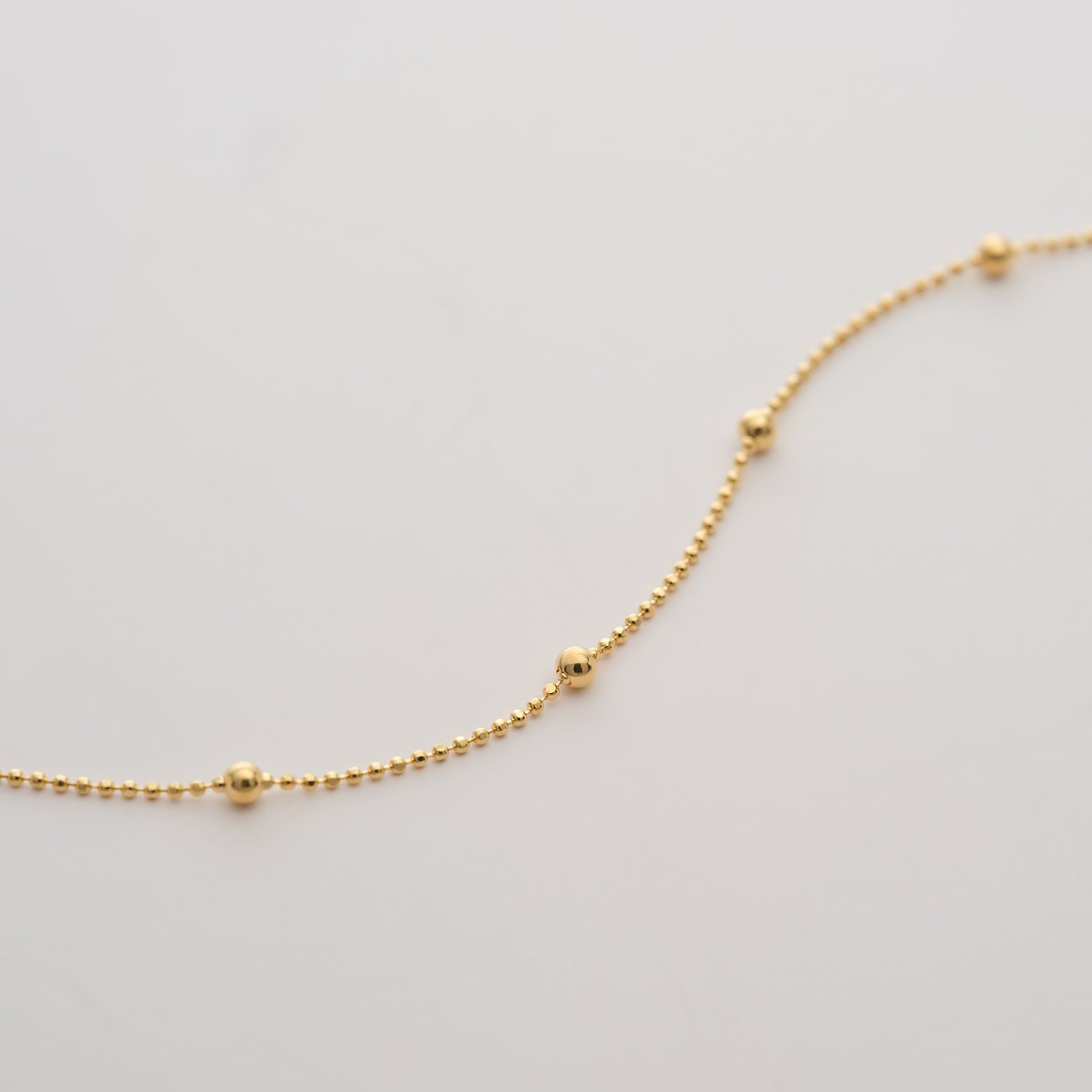 Nahaufnahme eines CHRIST 585 Gelbgold Armschmucks mit kleinen Kügelchen, diagonal über das Bild gelegt.