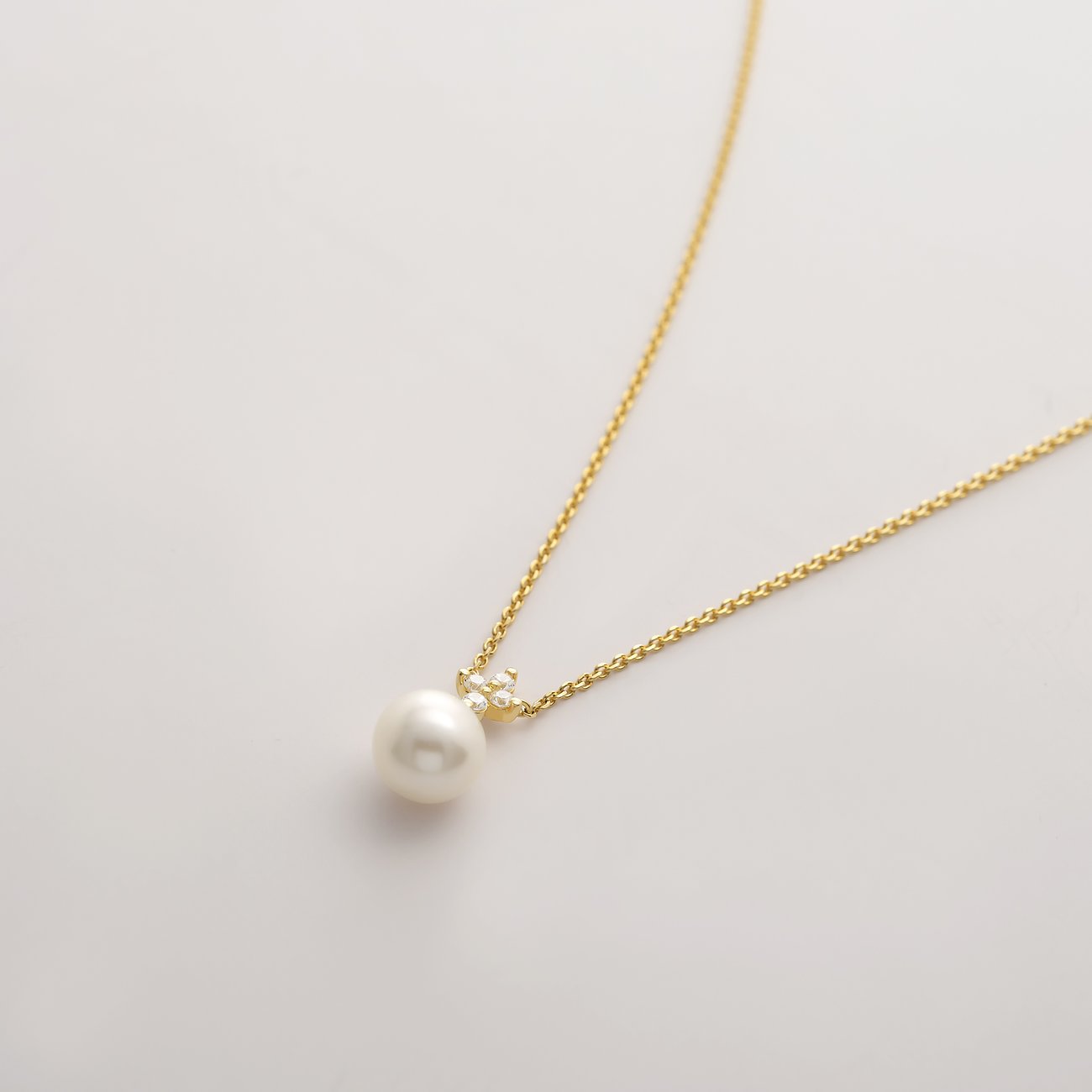 CHRIST necklace: white pearl, two clear gems on a delicate yellow gold chain.