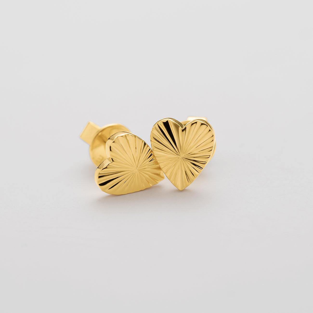 Guido Maria Kretschmer Ohrschmuck aus vergoldetem Silber. Zwei goldfarbene strukturierte Herzen nebeneinander.