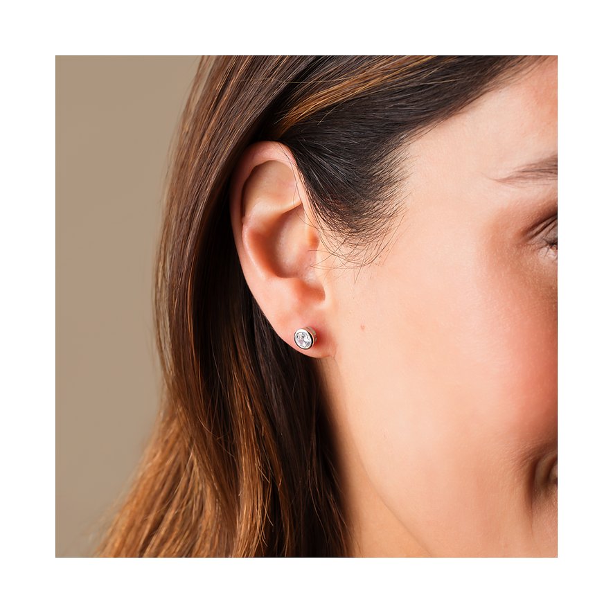 Gros plan d'une puce d'oreille FAVS en argent 925 sur l'oreille, sertie d'une zirkonia ronde et claire.