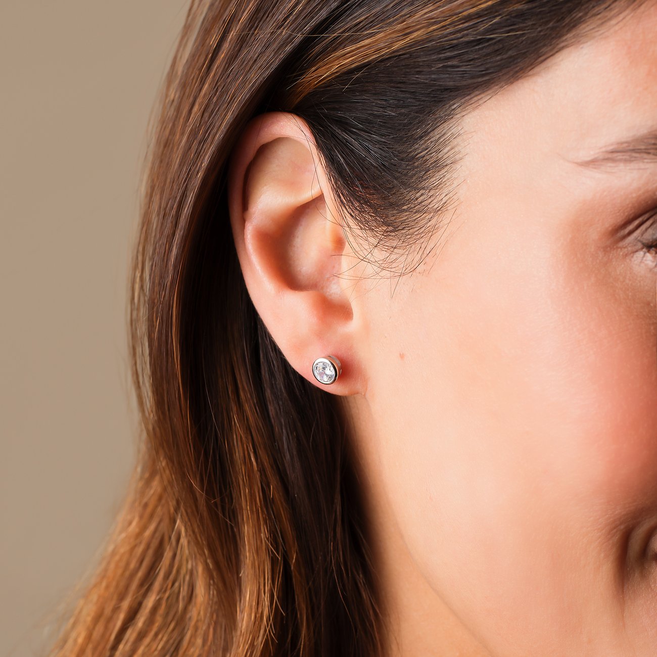 Gros plan d'une puce d'oreille FAVS en argent 925 sur l'oreille, sertie d'une zirkonia ronde et claire.