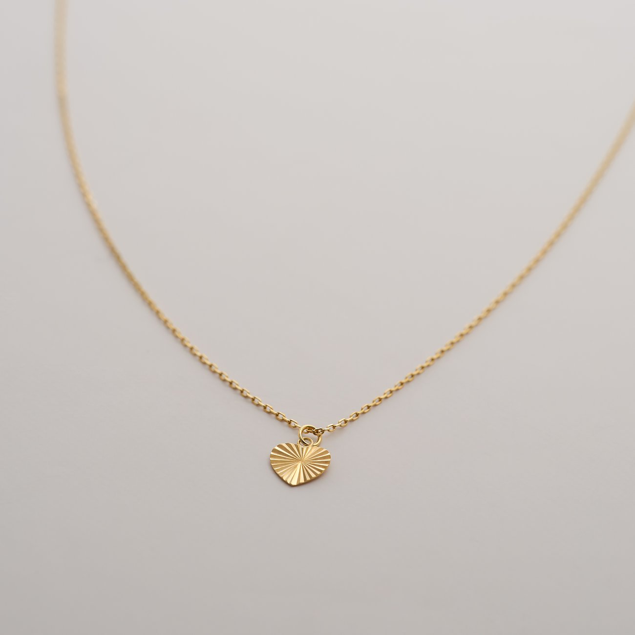 CHRIST Halsschmuck aus 375er Gelbgold mit einem Herzanhänger, fein detailliert mit gestreiften Linien.
