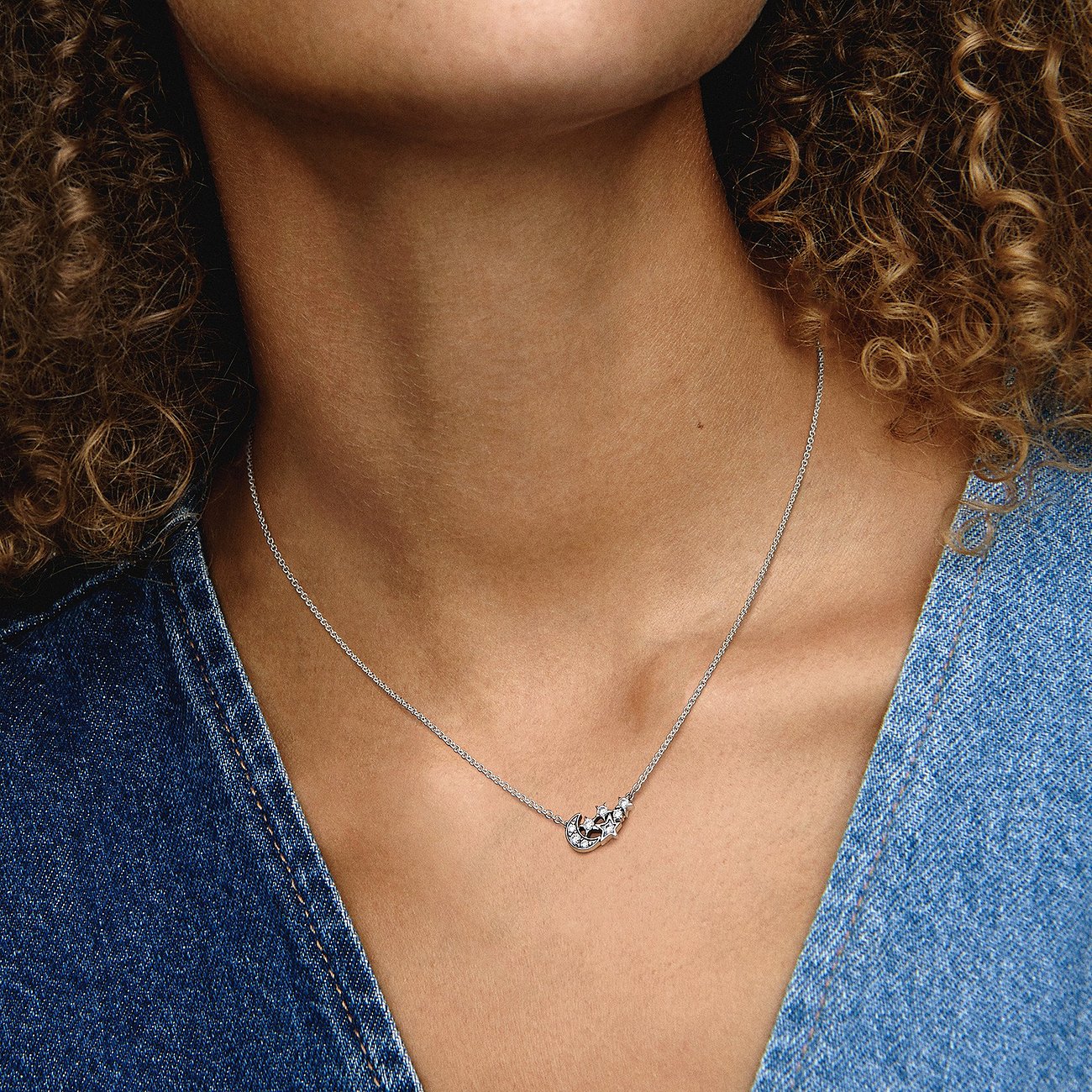 Am Hals getragen, eine kurze Pandora Feingliederkette aus Silber mit einem herzförmigen Anhänger, besetzt mit Zirkonia.
