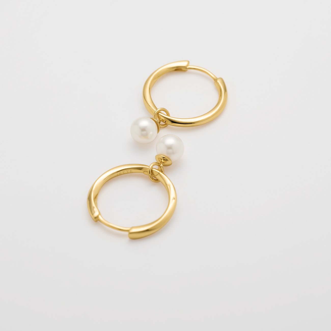 Une paire de boucles d'oreilles JETTE dorées en argent recyclé, avec une perle pendante à chaque créole.