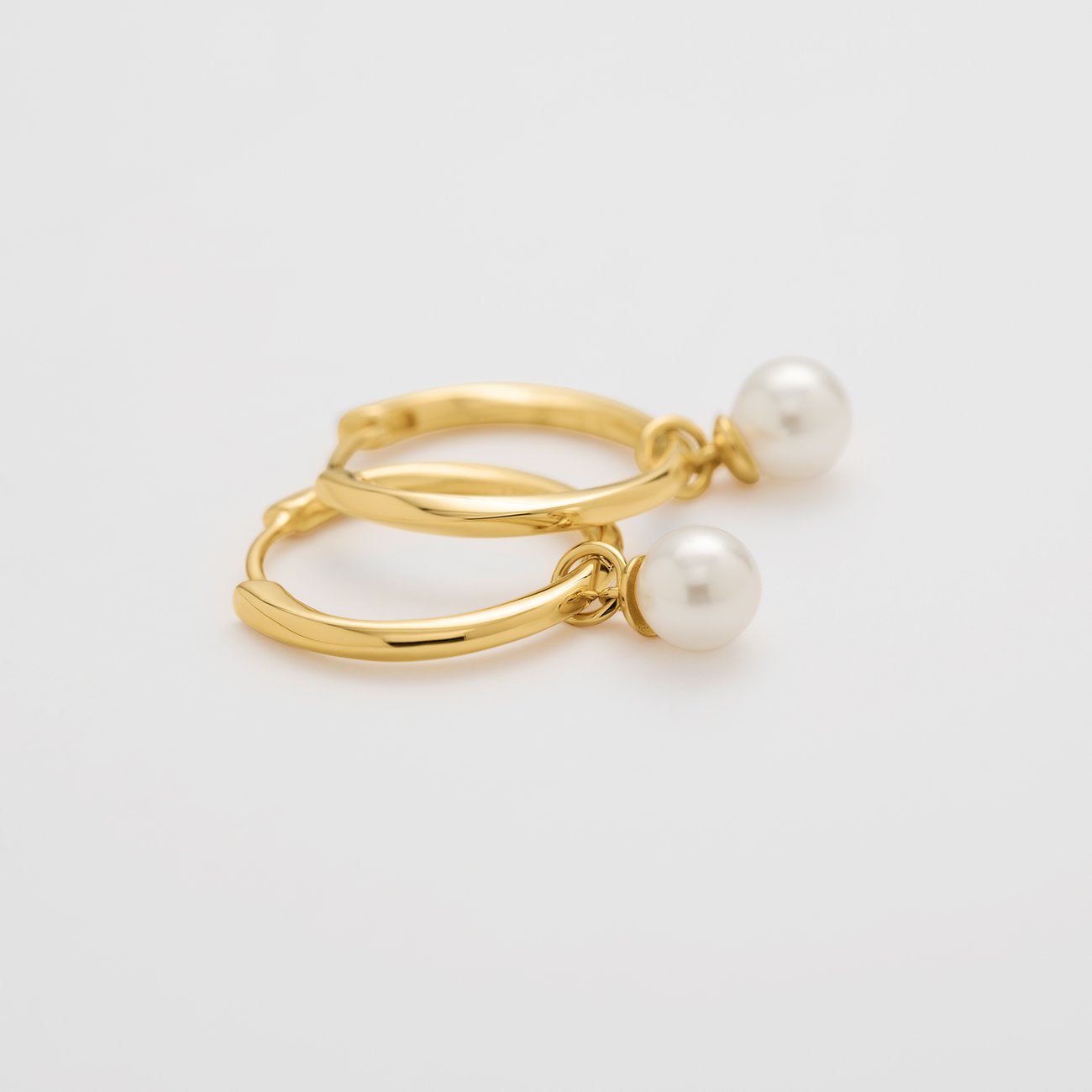 Boucles d'oreilles JETTE en argent recyclé avec perles, couleur or, légèrement décalées sur fond blanc.
