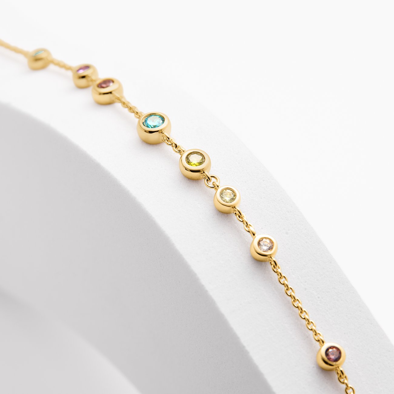 Nahaufnahme eines JETTE Armschmucks aus recyceltem 925er Silber, vergoldet, mit bunten Zirkonia-Farbsteinen.