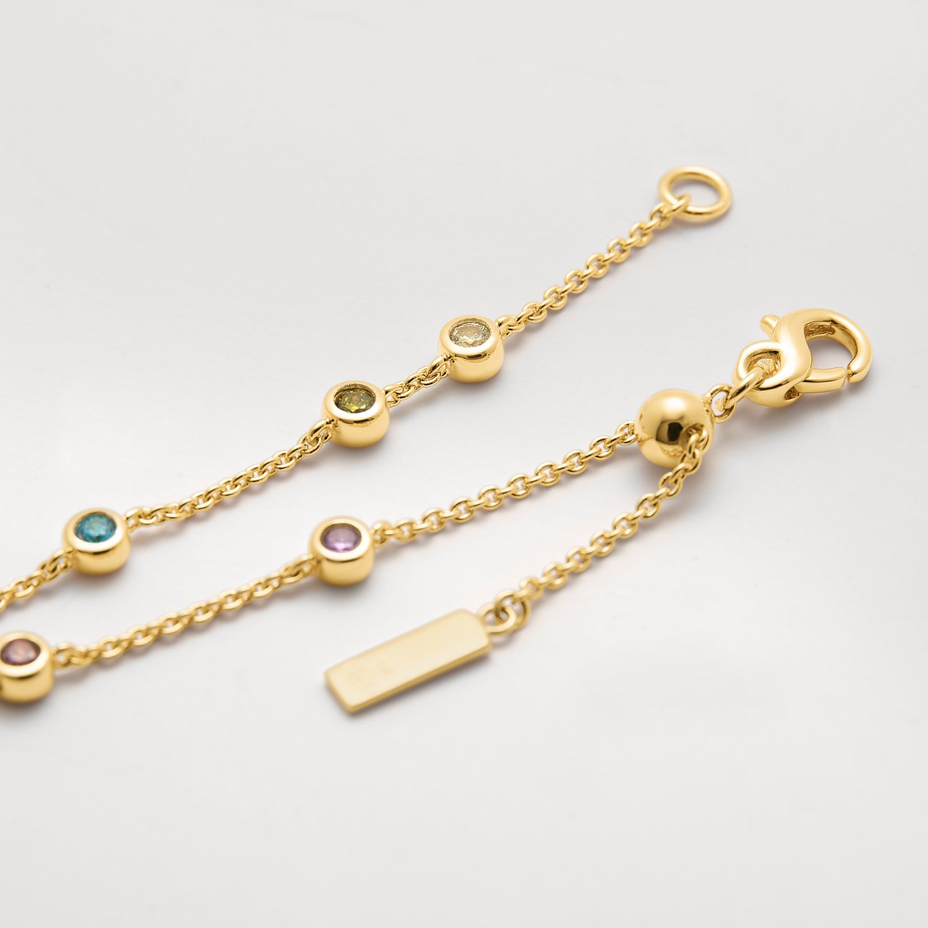 Nahaufnahme eines JETTE Armbands aus recyceltem, vergoldetem 925er Silber mit bunten Zirkonia-Farbsteinen.