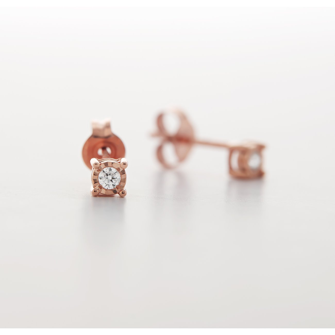 Ein funkelnder Ohrstecker von CHRIST aus 375 Roségold mit einem einzelnen Diamanten in Nahaufnahme.