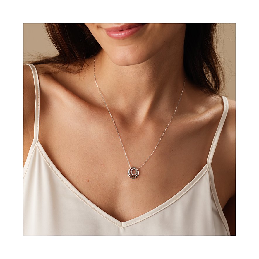 Nahaufnahme einer Frau mit einer CHRIST Halskette aus 585er Weißgold, Anhänger aus ineinander verschlungenen Ringen mit Diamanten.
