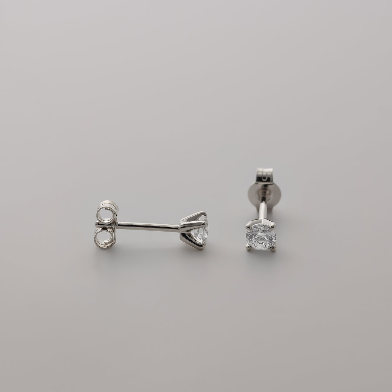CHRIST Ohrstecker aus 585 Weißgold mit funkelnden Diamanten, der eine liegt, der andere steht.